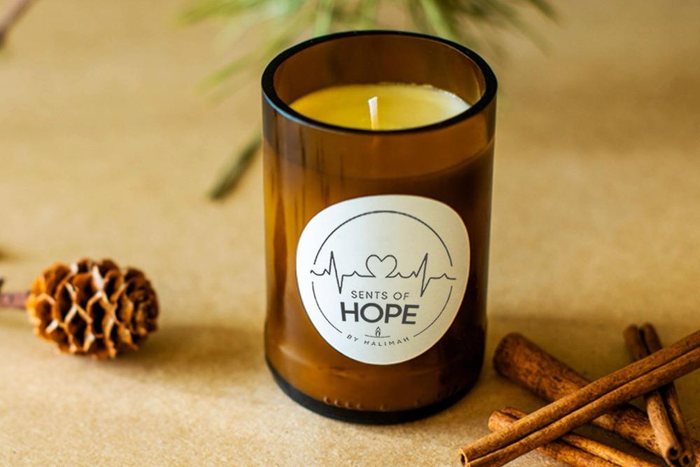 Scents of Hope logo on an amber glass candle jar